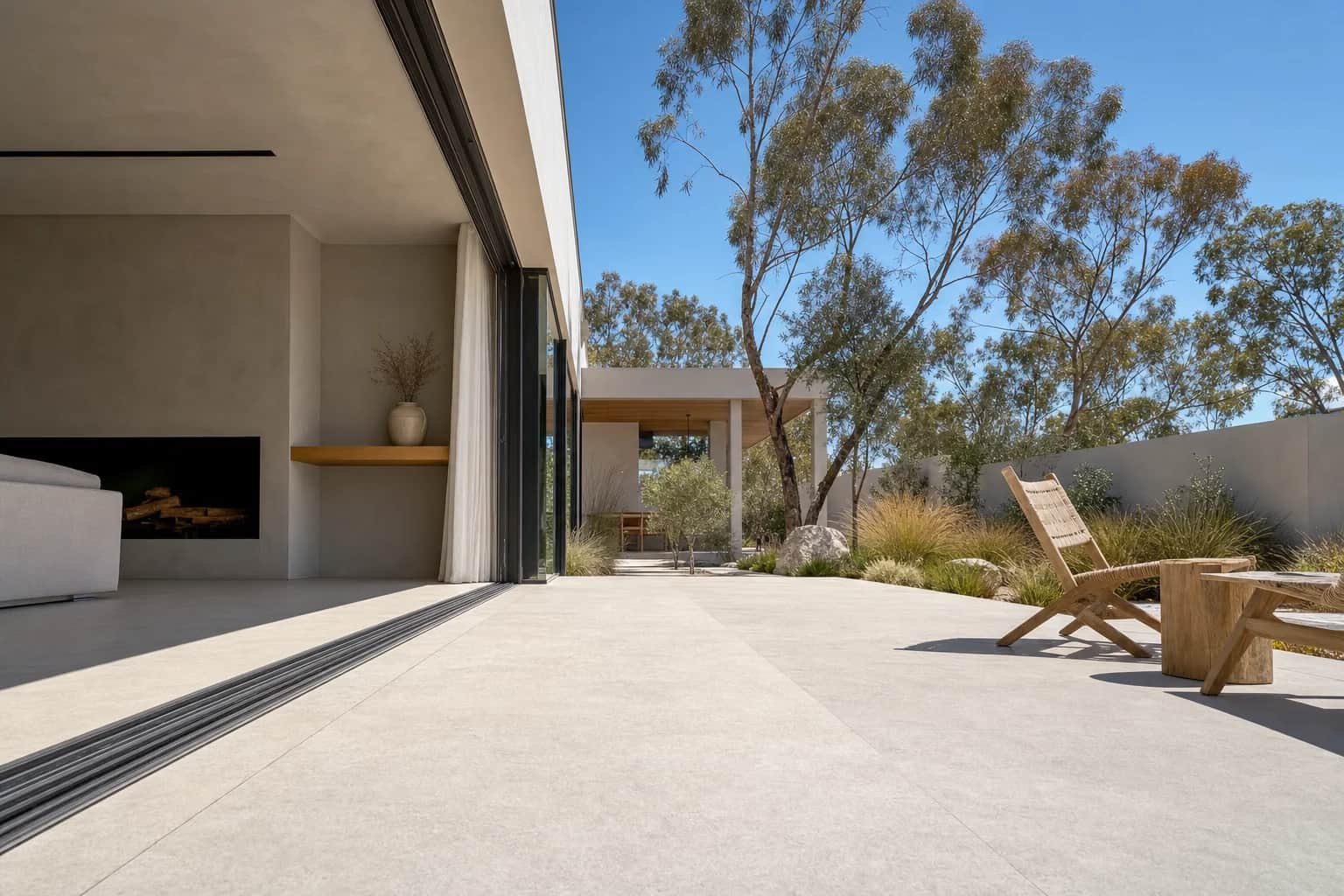 A sliding door open onto an alfresco with the same large format tile running flush from the indoor floor out onto the paving