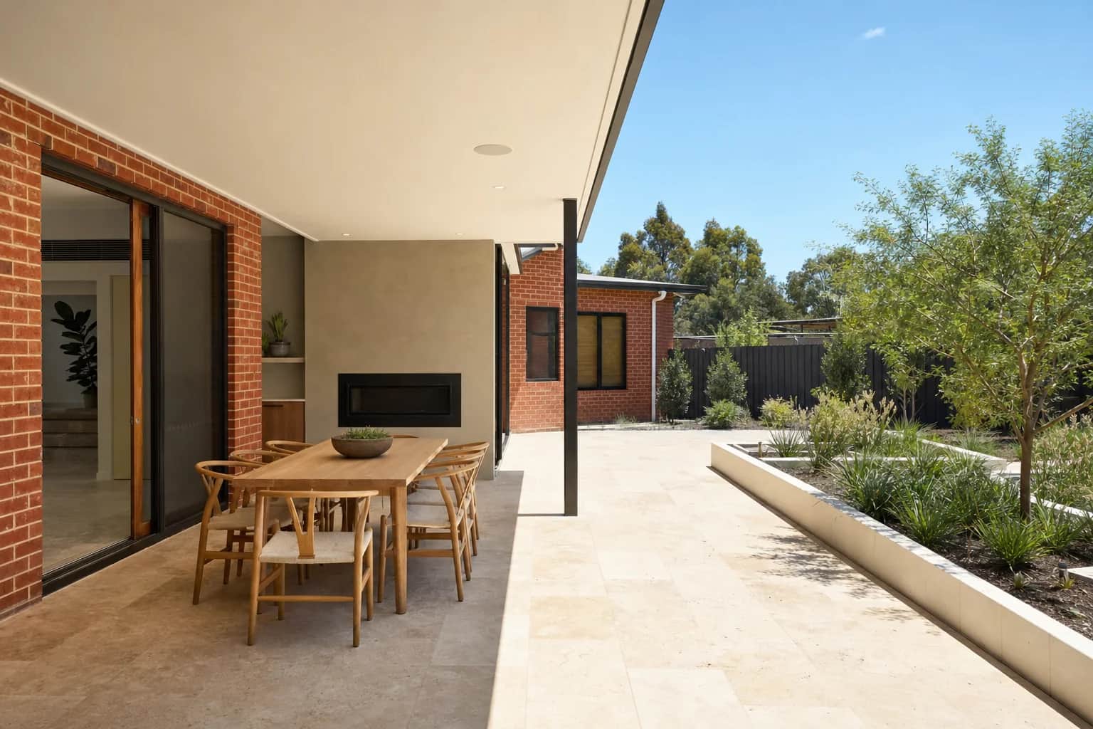 Pale limestone paving under an alfresco roof beside red brick, running out into full sun