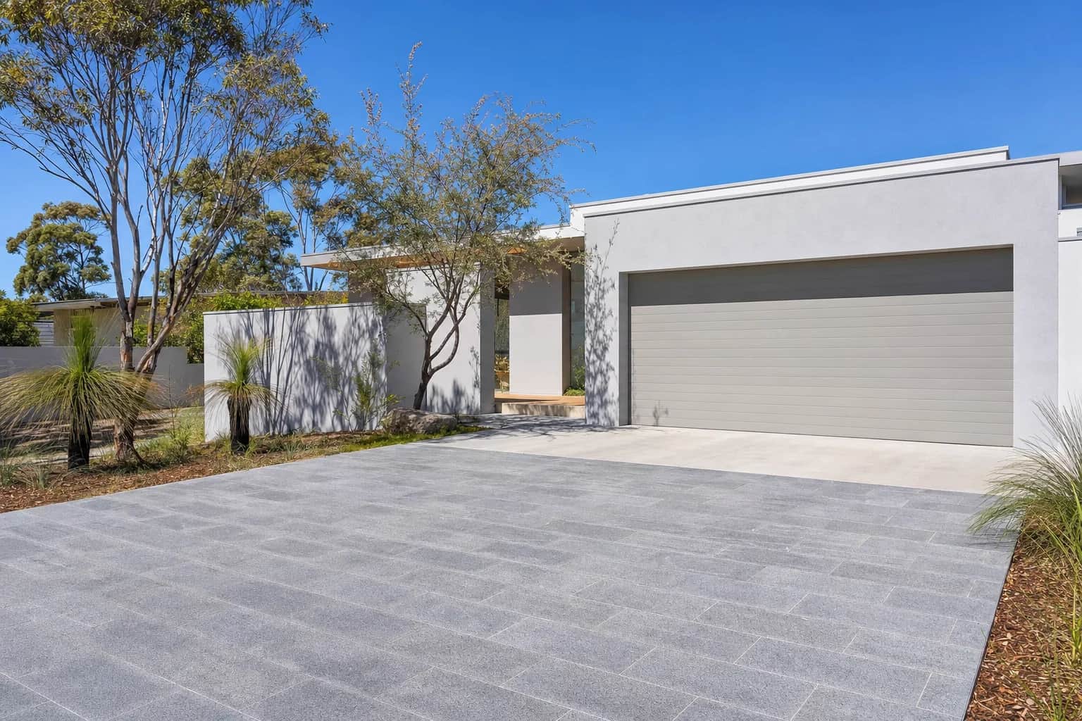 A newly completed driveway of grey large format stone pavers with crisp evenly grouted joints