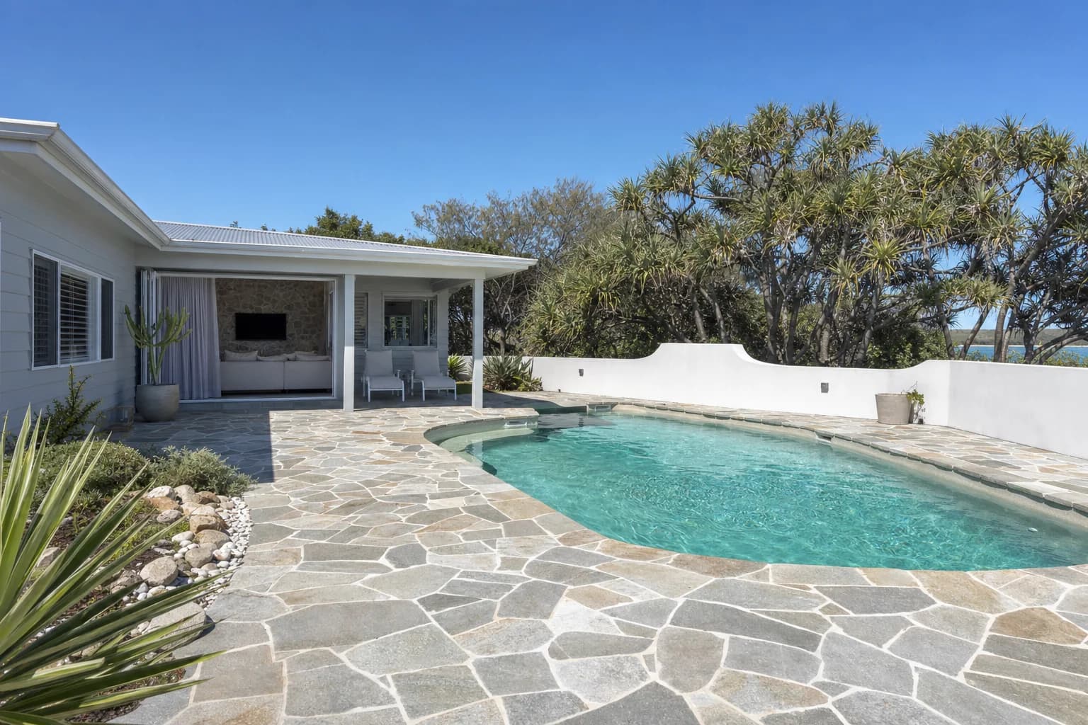 A Rockingham pool surround in crazy paving cut from grey and tan natural stone with tight grouted joints
