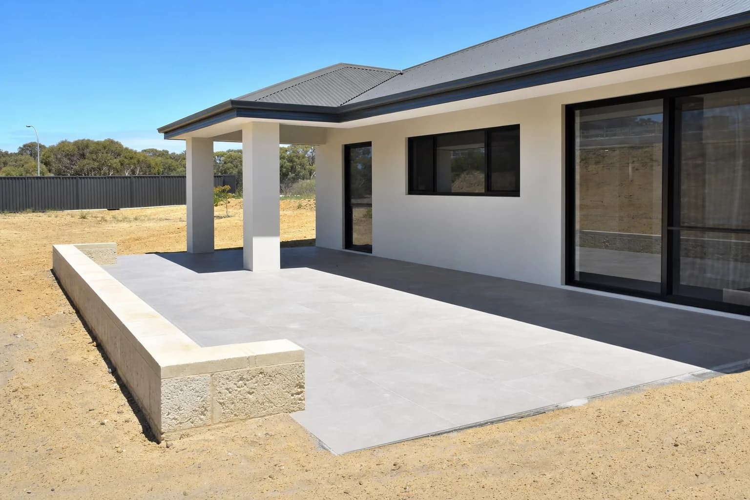 Large-format grey porcelain paving on a new alfresco area in Yanchep, builders sand still at the edges of an unlandscaped yard