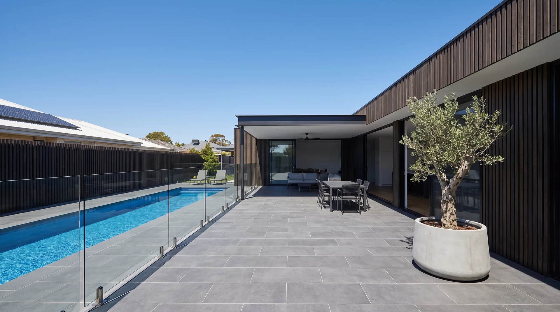 Large format charcoal porcelain pavers laid in a tight stack bond across an alfresco running out to a Perth lap pool