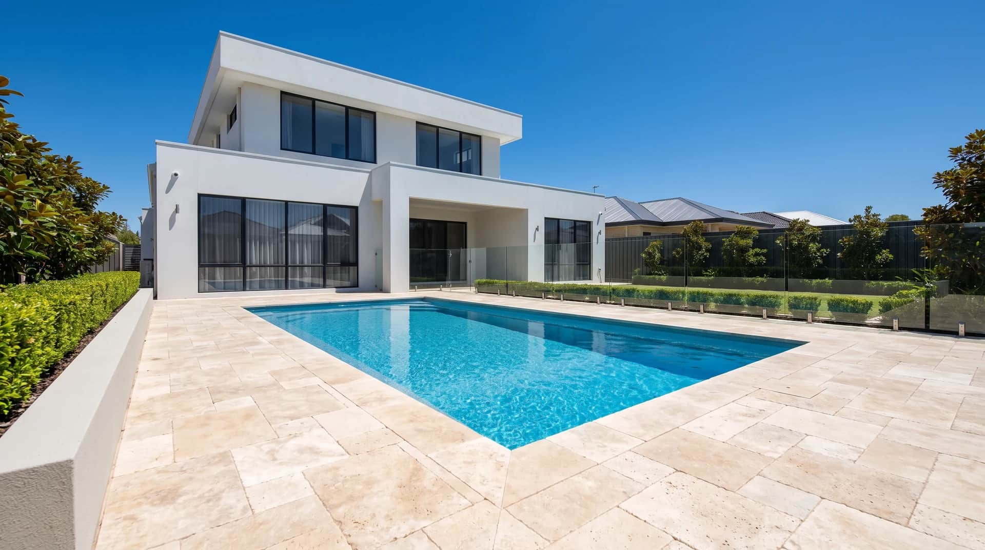 Cream tumbled travertine pavers laid in a French pattern around a rectangular pool at a Perth home