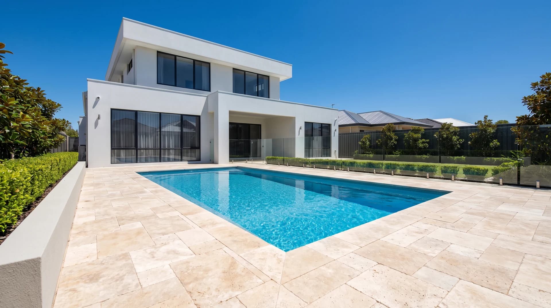 Cream tumbled travertine pavers laid in a French pattern around a rectangular pool at a Perth home