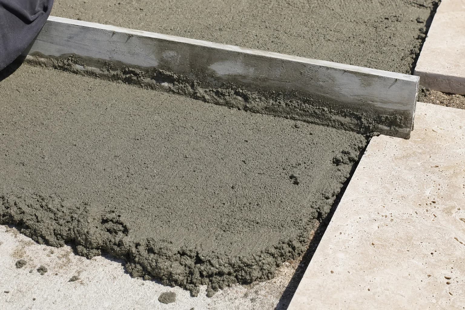 A wet mortar bed being screeded flat with a straight edge before paving is laid